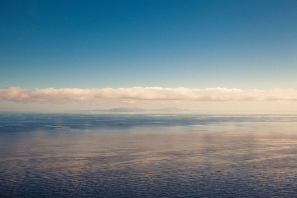 A placid see white clouds and sunset lighting