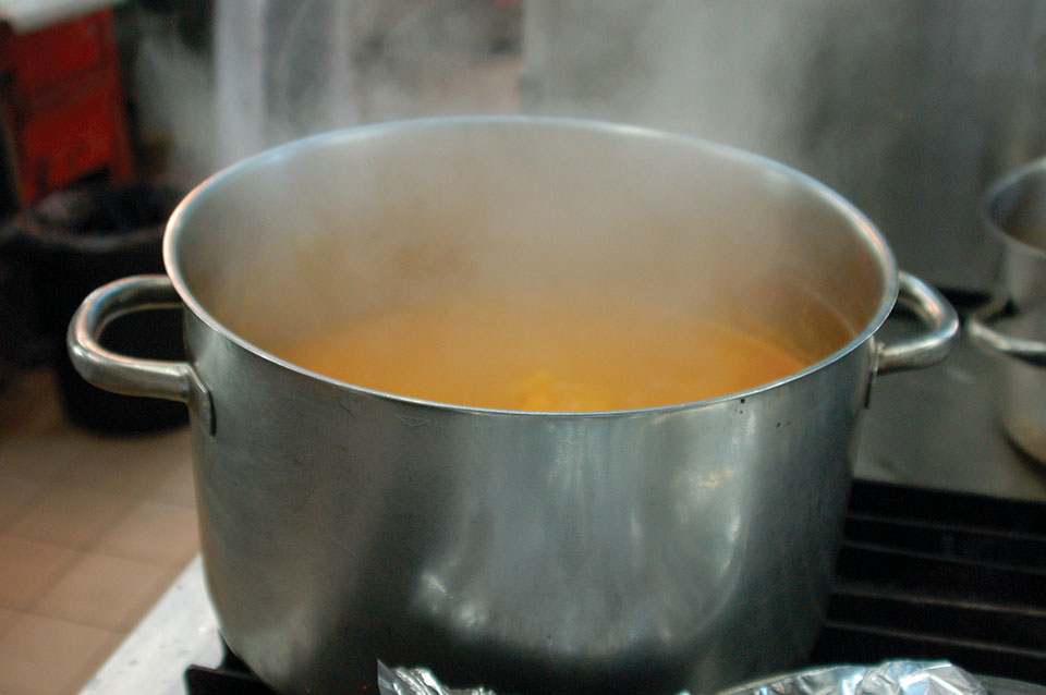 A photograph of a pot of broth steaming on a white stove