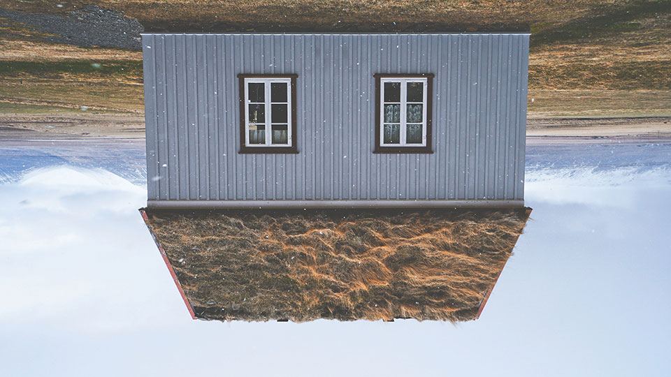 A photograph of an upside-down house with a cultivated sod roof 