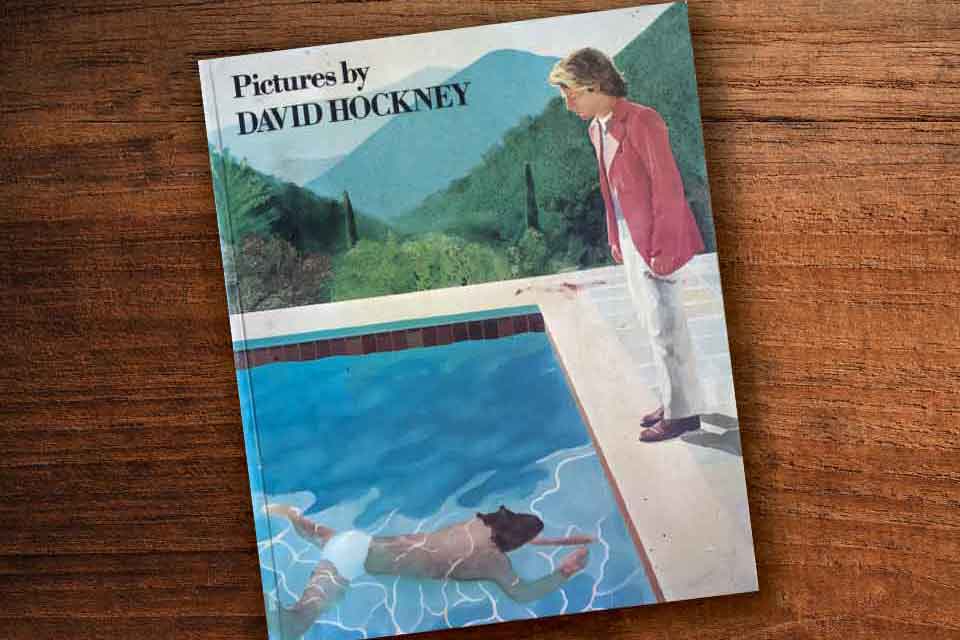 A photograph of David Hockney's book Photos laying on a wood grain table