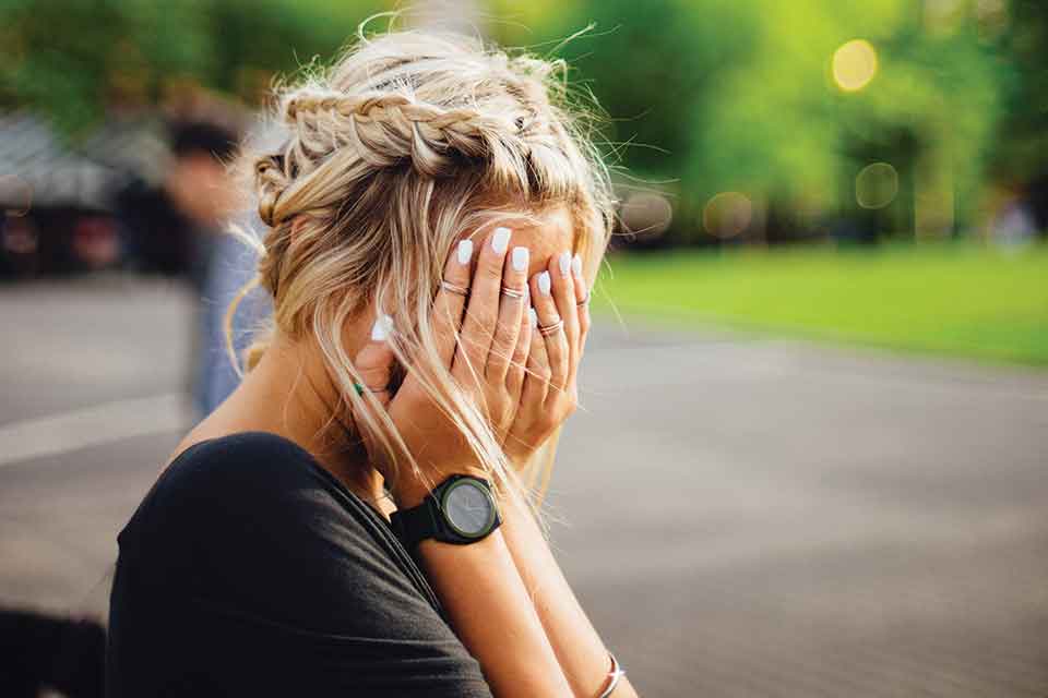 A photograph of a woman covering her face with her hands