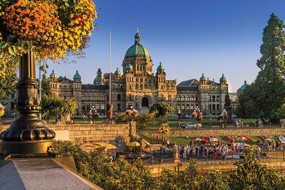 A photograph of. Parliament building, Victoria, BC; with inner harbor summer activities underway all around