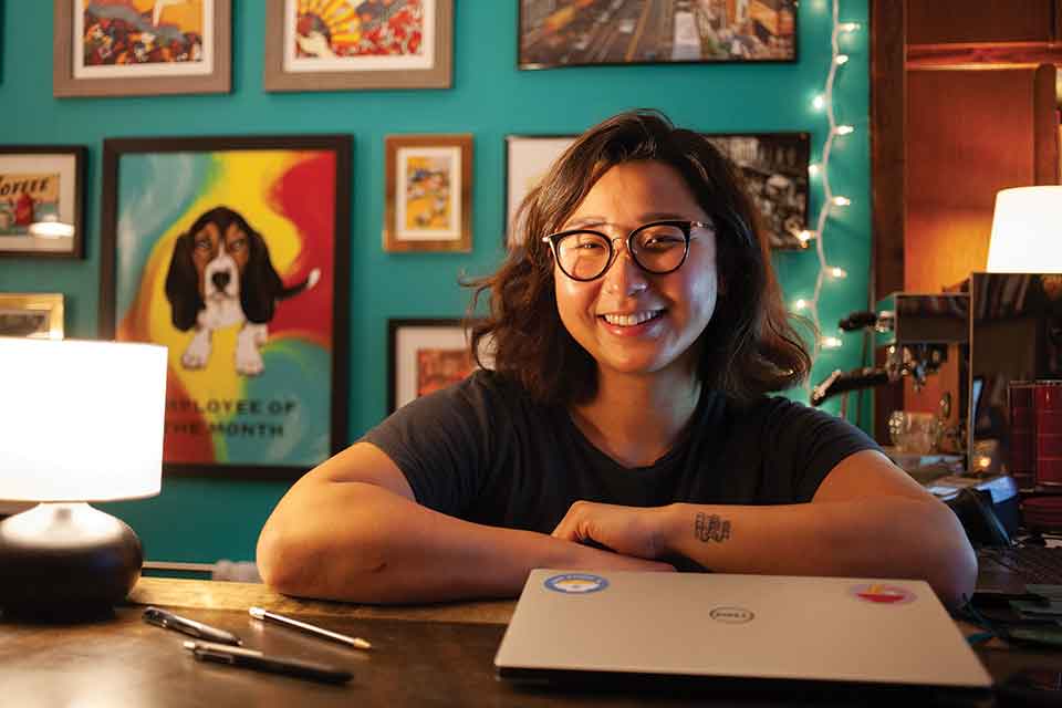 A photograph of bookstore owner Lucy Yu sitting at a desk with book open in front of her