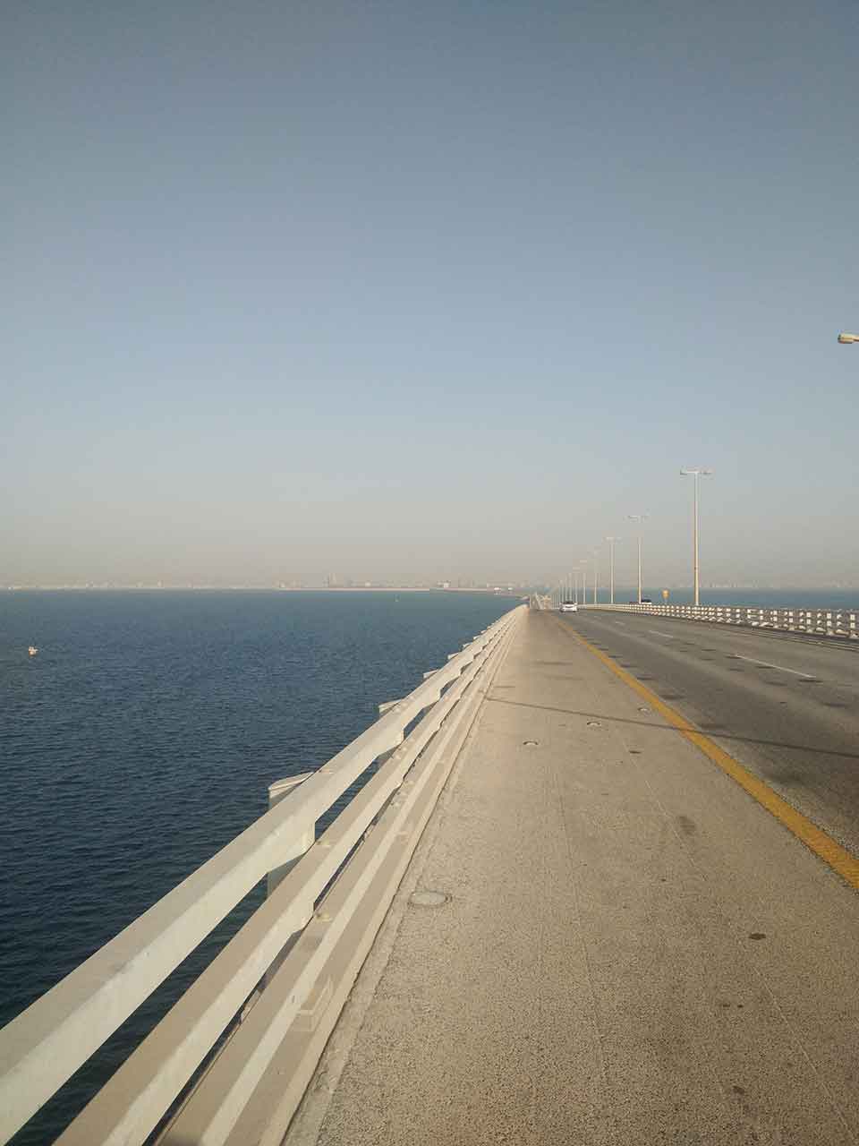 A photograph of a causeway stretching into the distance running beside a body of water