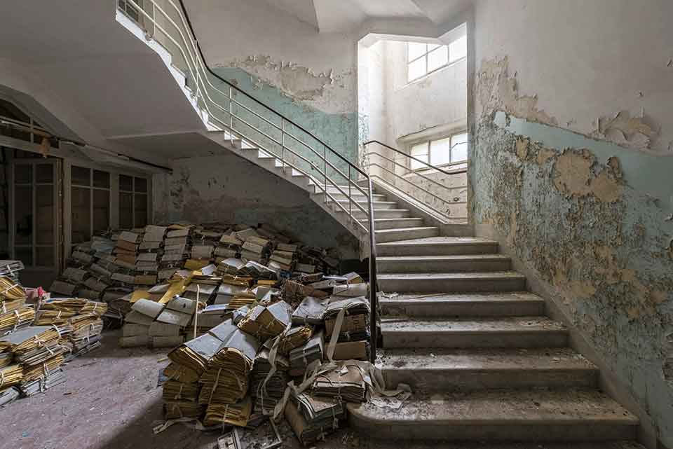 A photograph of a ruined library with a set of stairs rising up on the right side