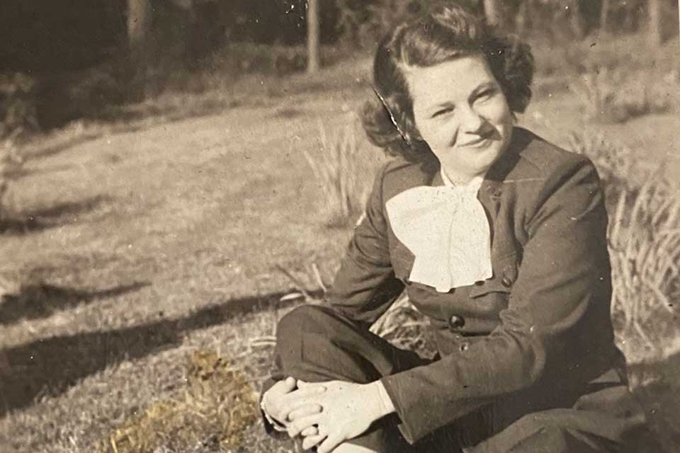 A sepia-toned photograph of a young woman sitting on a grass lawn.