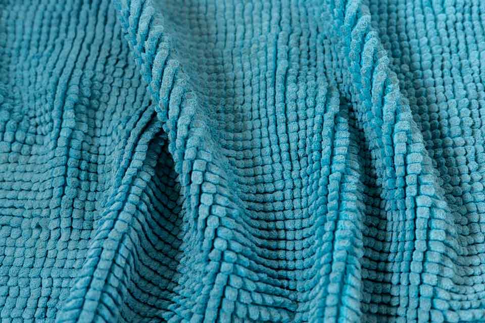 A close up photograph of the texture of a teal cloth