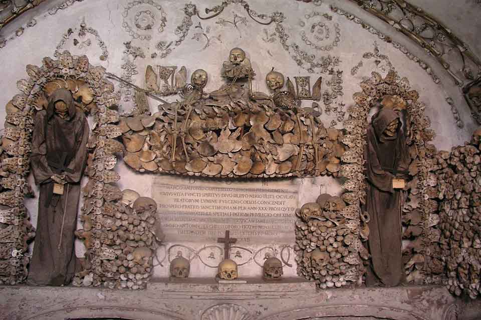 A diorama featuring two towering skeletal figures with hundreds of skulls creating the structure