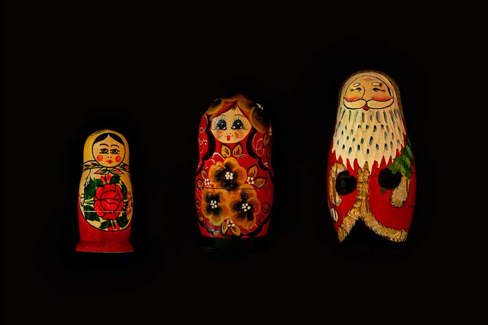 Three Christmas dolls laid side by side against a black background