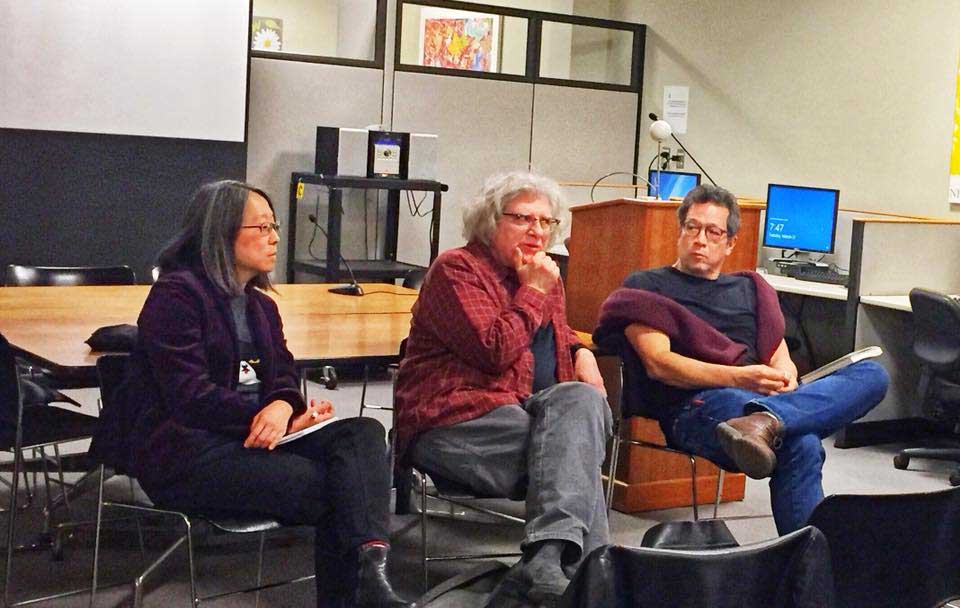 Three people sitting in chairs in conversation with an audience (which is off panel)