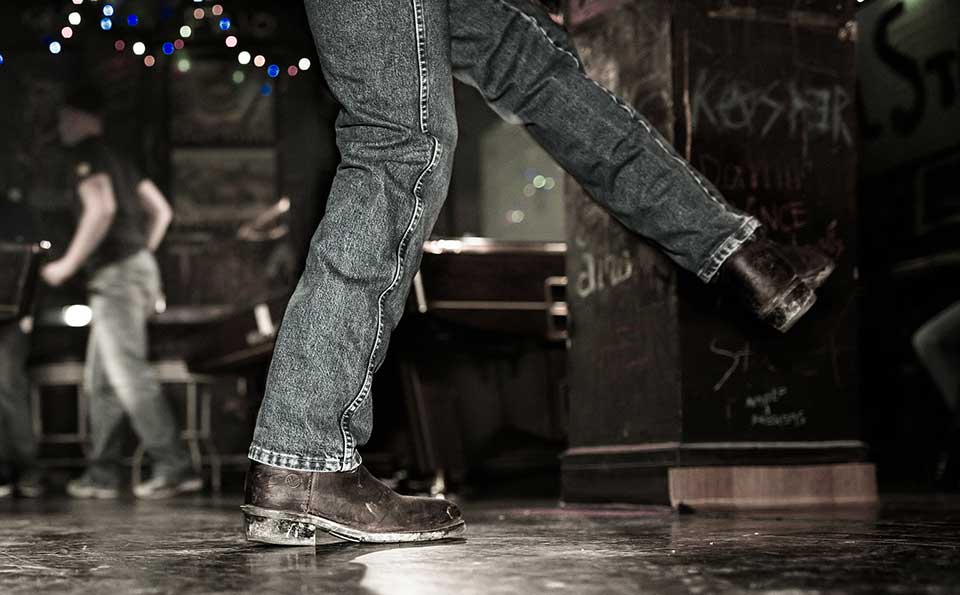 The legs of a dancer, clad in blue jeans and cowboy boots