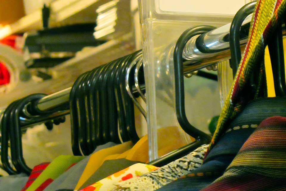 A close-cropped shot of a row of costumes on hangers in a long row. The focus is on the hangers.