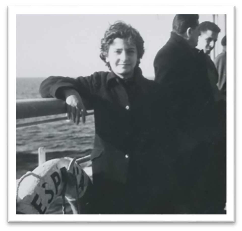 A black and white photograph of a woman leaning on a boat rail at sea