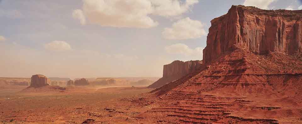 A photograph of a barren Western landscape, with a mesa in the foreground