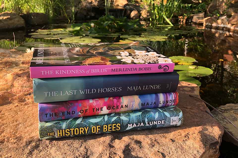 A photograph of the book discussed in the article below in a stack on a rock before a small pond