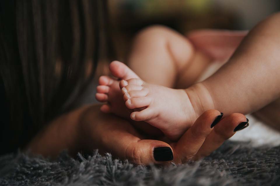 A close up photograph of a mother holding her baby's feet