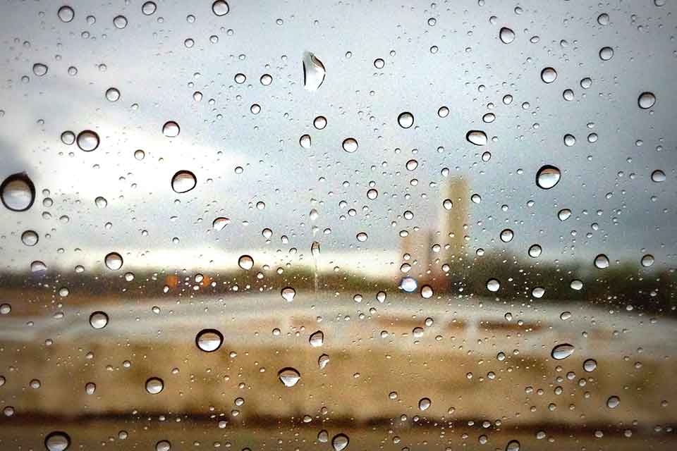 A photograph of a rural landscape, blurred by rain drops