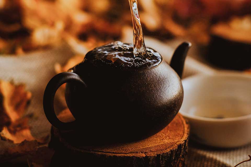 Water from above overfills the steeping basket of a tea pot