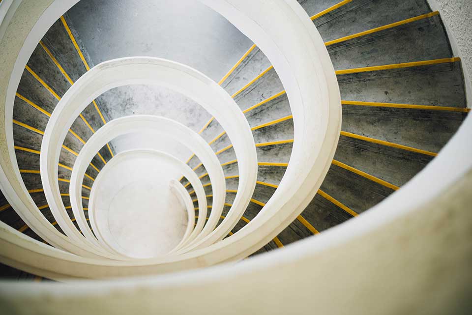 A photograph of a downwardly spiraling staircase, shot from above