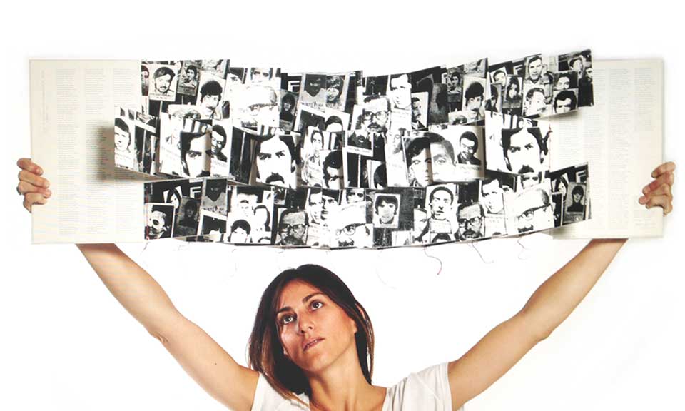 A woman holds up a book filled with illustrations above her head