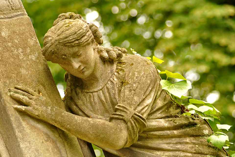 A photograph of a statue of a female figure clinging to a wall