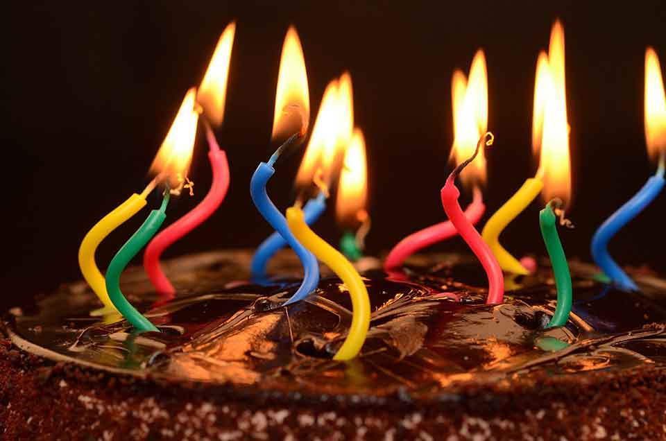 A photo of a chocolate birthday cake, its candles lit but strangely warped