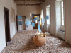 An elaborate installation. A wooden canoe sits in the middle of a room, the floor of which is covered in wood chips. Colored pieces of paper hang suspended in mid-air on string.