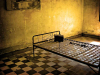 A photograph of a cot in a dimly lit prison cell