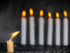 A photograph of six white candles burning