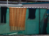 Clothes and other textiles hang on a chain-link fence surrounding tents