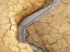 An aerial photograph of a dry river bed cutting through a dessicated landscape