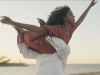 A photograph of a man holding a woman above his head