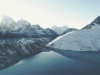 A landscape shot of snow-covered glaciers skirted by an apron of lakes