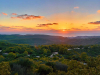 A photograph of an idyllic river valley with the sun rising in the background