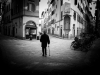 A black and white photo of a man using a cane staring at the buildings in an otherwise empty city