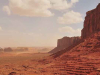 A photograph of a barren Western landscape, with a mesa in the foreground