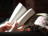 An open book in partial sunlight being held by a person with a blanket.