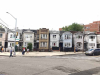 A panoramic shot of a urban street, mostly deserted with the exception of a small cluster of people near a streetlight