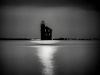 A black and white photograph of a building surrounded by water at night