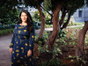 A photograph of Ada Límon who stands in front of a small tree garden