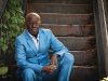 A photograph of Boubacar Boris Diop sitting on stairs looking at the camera