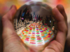 A polished steel ball held in a hand reflects a long table with colored plates on it