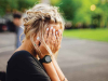 A photograph of a woman covering her face with her hands