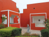 Two buildings, painted brightly red, intersect like angular puzzle pieces with a small green courtyard between them