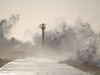 An observation tower rises out of the swirling froth atop a sea wall