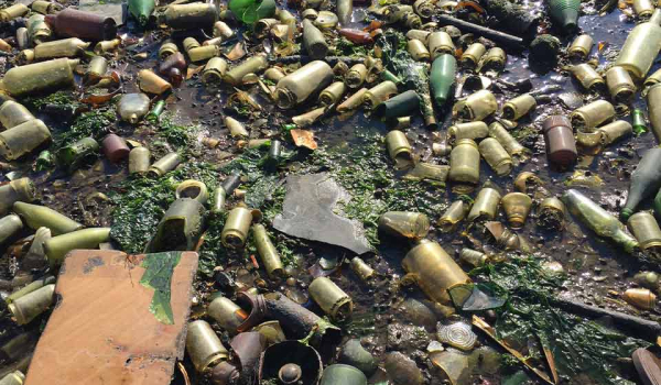 A closeup photograph of the sand on Dead Horse Bay, which is riddled with empty and broken bottles