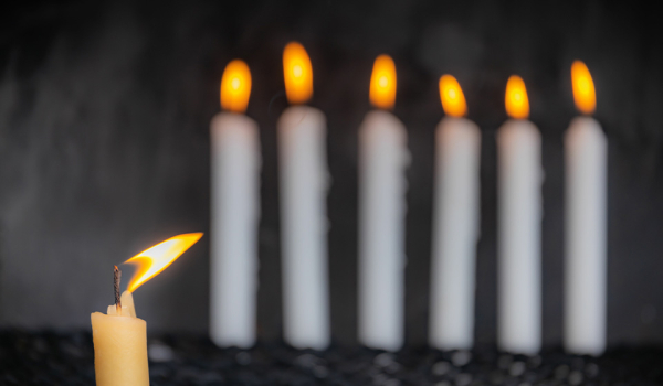 A photograph of six white candles burning