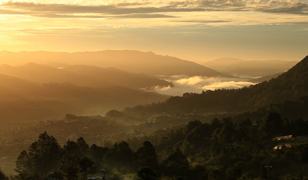 A photograph looking from up on high down at a river valley in the golden morning sun