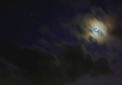 Crescent moon behind clouds. Photo by Adam Evans/Flickr