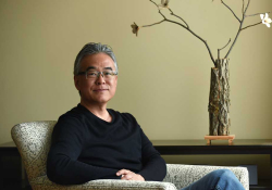 A photograph of Aaron Caycedo-Kimura seated in a chair